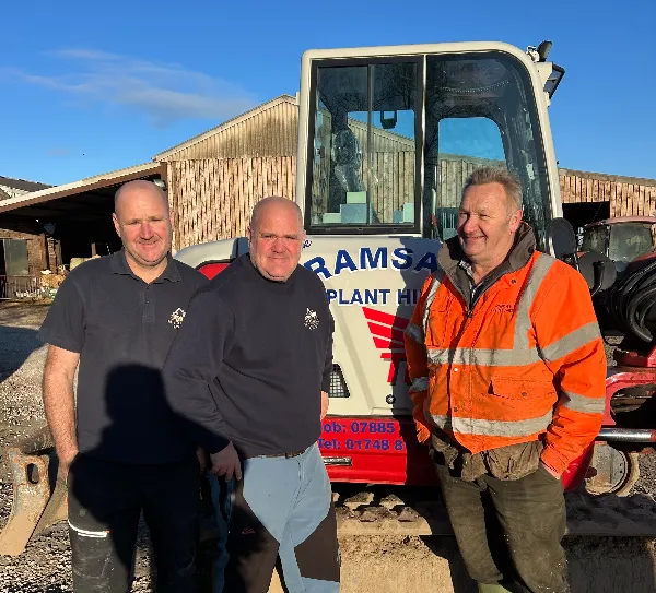 three men stood infront of a machine